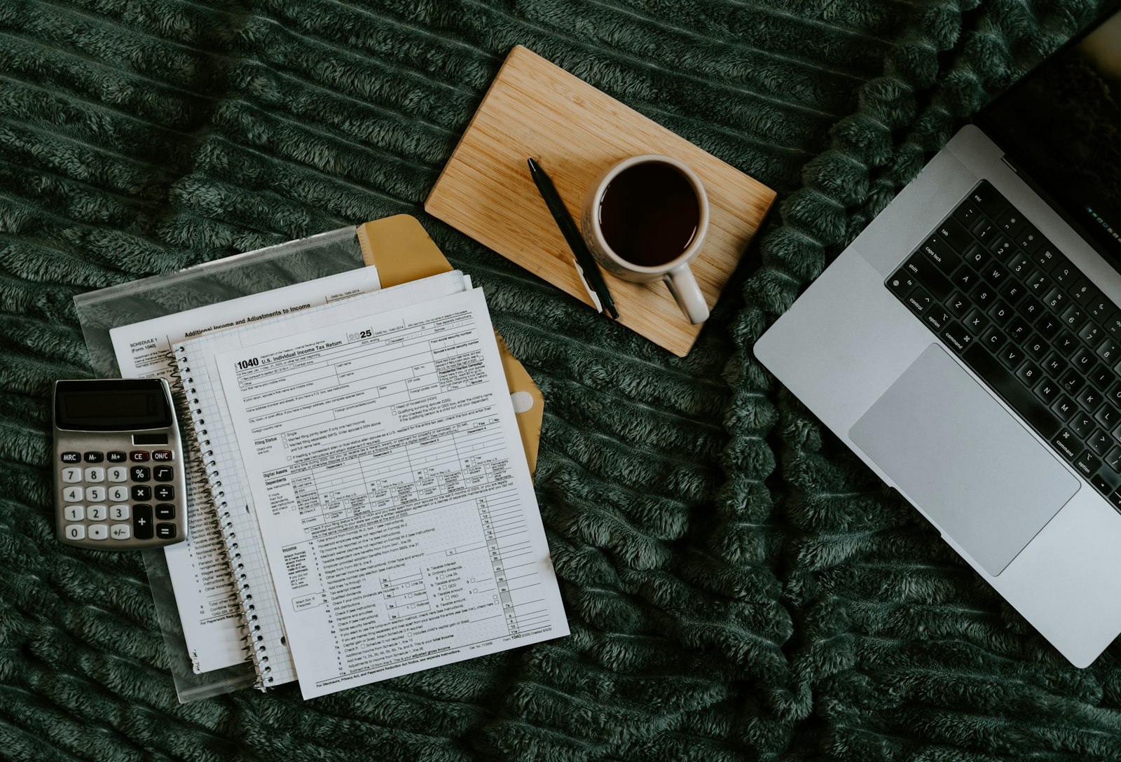 Laptop, papéis, calculadora e café sobre uma mesa, representando análise financeira do negócio